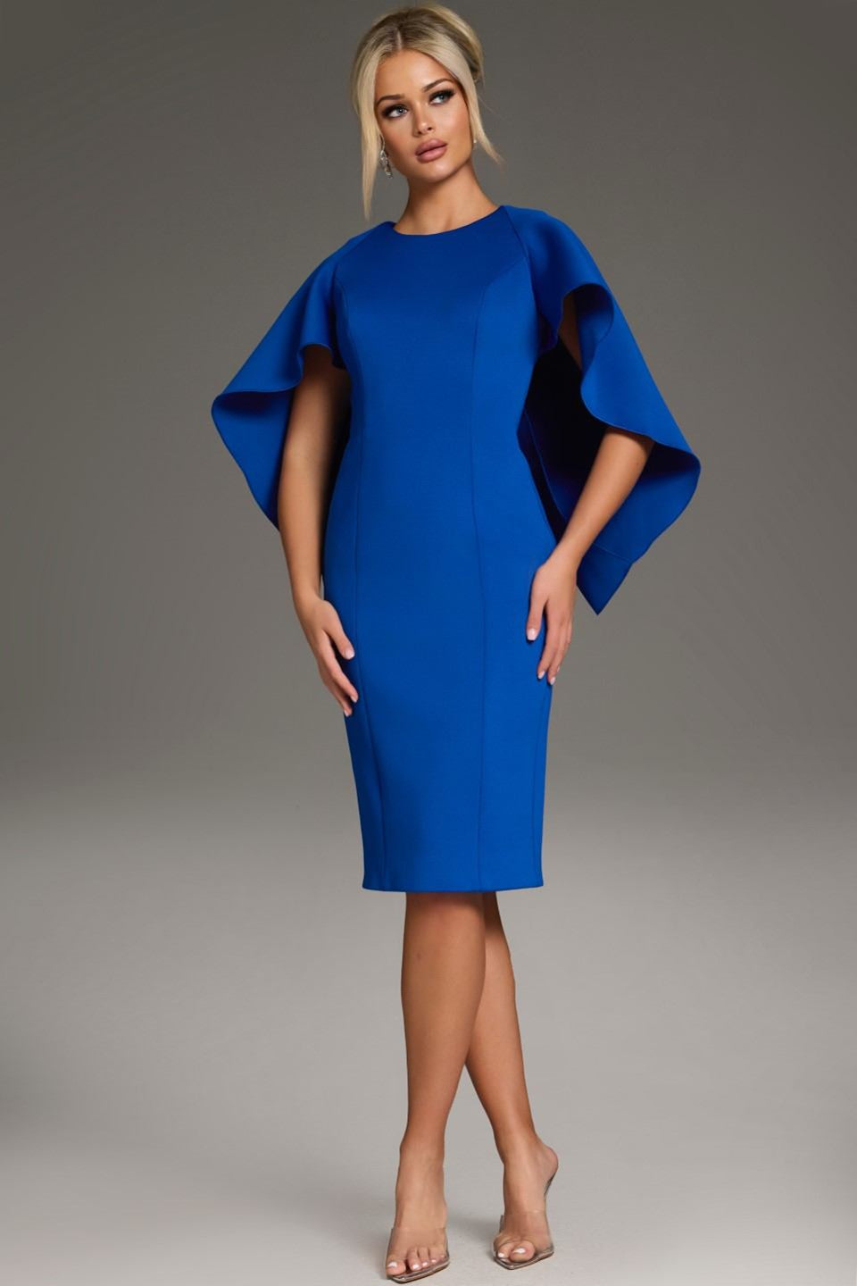 Turn heads in the Jovani 38824 cocktail dress! This knee-length scuba dress features a chic crew neckline and a playful cape detail, making it perfect for parties and special events. Shop now at FOSTANI 